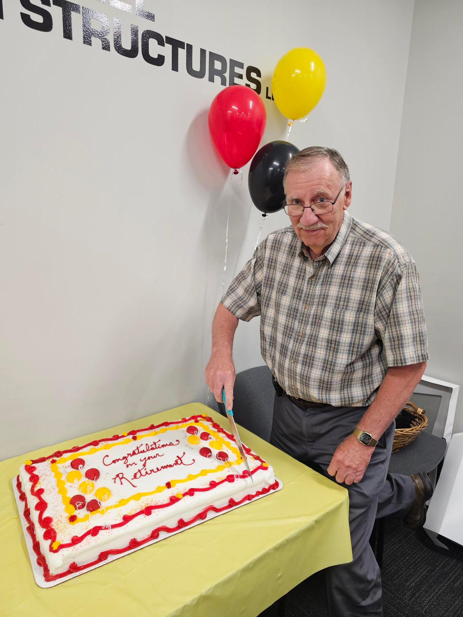 Geoge cuts his retirement cake on July 15, 2025
