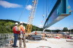 Workers on the eastbound span roadway watch the installation of the project's final girder.